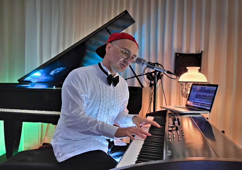 Bastian Lee Jones singing and performing at a stage piano with microphone and recording setup in his studio.