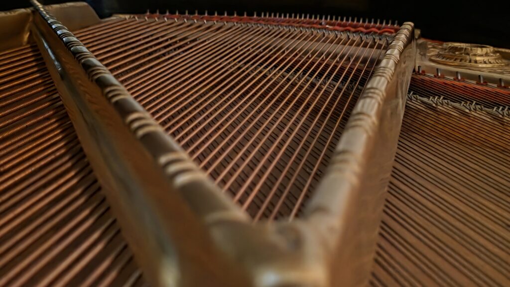 Interior detail of Bastian Lee Jones’s historic Grotrian-Steinweg grand piano showing strings and soundboard.