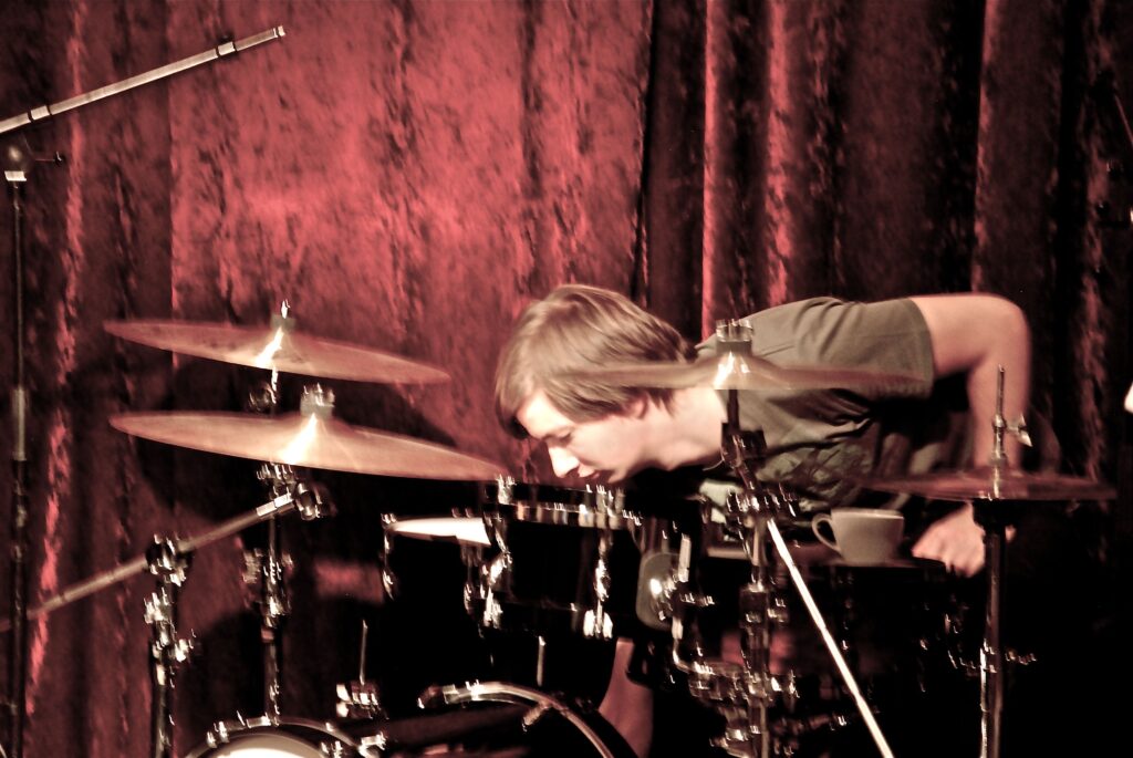 Drummer leaning over a drum kit during rehearsal or performance.