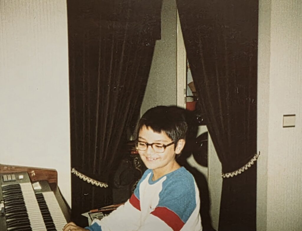 Young Bastian Lee Jones smiling while seated at a Wersi organ during childhood.